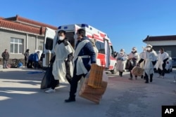 中国河北高碑店火葬场内逝者的亲属身着孝服手拿祭品走过。(2022年12月22日)