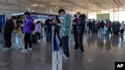 旅客在北京首都国际机场国际航班值机柜台办理登机手续后使用智能手机填写健康申明。(2022年12月29日,资料照片)