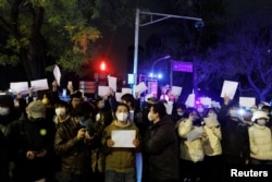 2022年11月28日,在中国北京,随着新冠肺炎疫情的持续,人们在为乌鲁木齐火灾遇难者守夜后,手持白纸抗议新冠肺炎疫情限制措施。