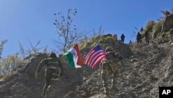 2022年11月30日,印度和美国陆军士兵举着各自国家的国旗,在印美联合演习期间跑上一座小山。 (美联社照片)