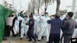 中国河南郑州富士康代工厂里身穿防护服的警察和保安殴打参加示威活动的工人。(2022年11月23日)