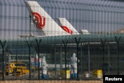 北京国际机场身穿防护服的工作人员站在中国航空公司的飞机附近。(2023年1月6日)