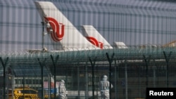 北京国际机场身穿防护服的工作人员站在中国航空公司的飞机附近。(2023年1月6日)