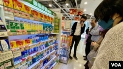 香港一间连锁药房的感冒止痛药货架前,聚集多名顾客围观,等待含扑热息痛的防疫药物上架 (美国之音/汤惠芸)