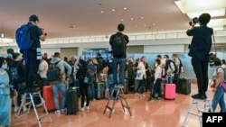 资料照:日本因新冠疫情边控外国游客来日本观光旅游两年半后,于2022年10月首次开放。新闻记者站在梯子上为抵达日本羽田国际机场的外国游客拍照。(2022年10月11日)