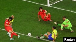 Jwe Sid Koreyen Son Heung-min choute balon an nan direksyon gol la pandan ko-ekipye li Cho Gue-sung ak Brezilyen Marquinhos ak Alisson reyaji, 5 Desanm, 2022.