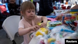 2022年4月13日,在蒂华纳当地政府设置的避难所内,一名在美国寻求庇护的乌克兰儿童在玩复活节主题的拼图。(路透社)