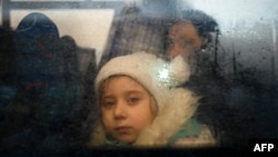 资料照:2022年3月2日,一名逃离乌克兰冲突的女孩在穿过帕兰卡附近的摩尔多瓦-乌克兰边境检查站后从一辆开往摩尔多瓦首都基希讷乌的巴士里朝外看。(法新社)