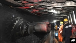 在新华社发布的这张照片中,中国东部安徽省宿州市前营子煤矿的矿工们2021年10月20日在机器旁劳动。