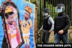 中国驻曼彻斯特领事馆工作人员走向领馆外由反中共二十大示威者竖立的中国领导人习近平的漫画。(2022年10月16日)