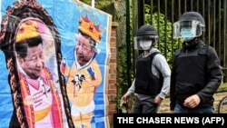 中国驻曼彻斯特领事馆工作人员走向领馆外由反中共二十大示威者竖立的中国领导人习近平的漫画。(2022年10月16日)