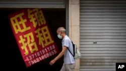 一名男子走过北京街头一家招租的商铺。(2022年8月17日)