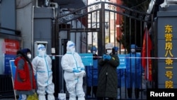 资料照片:“大白”站在北京东营房一个被封居民小区的大门口。(2022年10月22日)