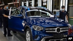 资料照 - 2020年5月在北京的北京奔驰汽车有限公司的汽车装配线上,工人们正在检查装配中的奔驰轿车。