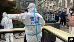 图为2022年4月1日,上海静安区的警察指挥居民排队等待核酸检测。