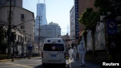 上海街头停着的120急救车旁走过身穿防护服的人。(2022年4月16日)