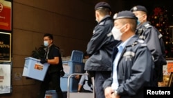 资料照:2021年12月29日,香港一名警察在搜查了《立场新闻》办公室后收集了一箱证据。(路透社)