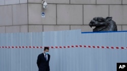 上海一家商场围栏外走过一名戴着口罩的工作人员。(2022年4月20日)