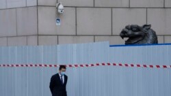 上海一家商场围栏外走过一名戴着口罩的工作人员。(2022年4月20日)