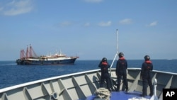 2021 年 4 月 27 日,菲律宾海岸警卫队提供的照片中,其人员在南海萨宾娜浅滩的据称是中国民兵船的船只旁边巡逻。菲律宾政府抗议中国海警...