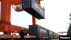 资料照:中国浙江省义乌火车站的一名工人在给开往欧洲的火车上装载集装箱。(2017年4月15日)