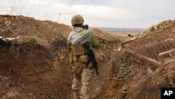 资料照片：一名乌克兰士兵抱着猫走在顿涅斯克地区与亲俄分离武装的分界线战壕里。(2021年12月3日)