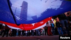 FILE - Supporters rallying for the nation’s peace agreement with FARC hold a giant flag during a march in Bogota, Colombia, Nov.15, 2016.