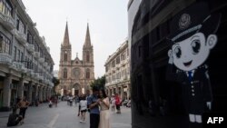 2018年9月22日,中国游客在广东省广州市的圣心大教堂(也称为耶稣圣心大教堂或石狮天主教堂)前拍照。旁边是警察的漫画形象。