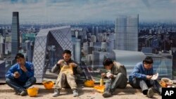 北京一个建筑工地外面,工人吃午饭,旁边的板子上有中央商务区的影像