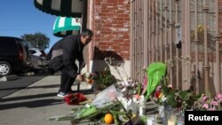 2023年1月23日加利福尼亚州蒙特利公园发生大规模枪击事件后,一名男子在明星舞厅入口处点燃蜡烛