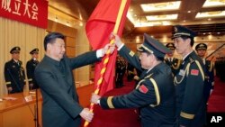 资料照:中共领导人习近平在北京举行的中国人民解放军战区成立大会上向火箭军将领、中国防长魏凤和(中)授予军旗。(2015年12月31日)