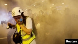 在香港警察向反送中示威者发射催泪弹后一名记者用手掩住口鼻。(2019年8月4日)