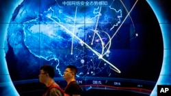 资料照片:在北京举行的互联网安全大会期间,人们走过表示近期在中国发生的网络袭击的电子显示屏。(2017年9月12日)
