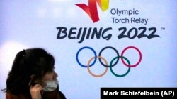 资料照片:一名女性在北京邮电大学内的北京冬奥广告前(2021年12月9日)