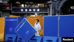 上海一名身穿防护服的工作人员站在封城使用的围栏旁。(2022年4月11日)