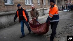 2022年3月23日,在乌克兰基辅,邻居们从被炮击的公寓里搬出被打碎的窗户玻璃碎片。(美联社)