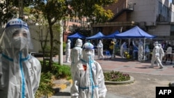 身穿防护服的工作人员在上海静安区的一个测试点看着居民做新冠病毒测试。(2022年4月4日)