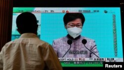 香港市民在街上的电视机前观看香港特首林郑月娥在4月4日记者会上宣布不会参选连任特首的消息