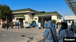 人们身穿防护服站在上海的一家火葬场外。(2022年12月24日)