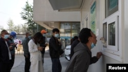 资料照片:在北京与河北省的交界附近的新冠病毒检测站,一位男子张开嘴接受检测。(2022年4月20日)