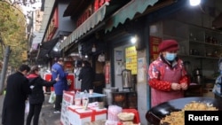 中国政府放宽清零政策后,湖北武汉街头人们在小摊前排队购物。(2022年12月10日)