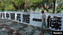 资料照:一名男子走过台北街头悬挂的写有“投资中国死路一条”字样的标语。(2012年8月8日)