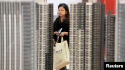 资料照:湖北武汉一名女子正在一个新楼盘售楼处观看。