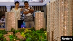 资料照:北京市民在房地产交易会上观看公寓楼模型。(2010年6月24日)