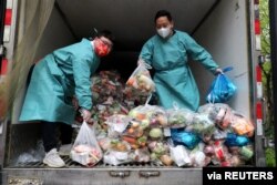 身穿防护服的工作人员把卡车里的蔬菜分发给上海居民。(2022年4月5日)