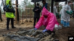 一名专家在乌克兰伊久姆对一名被发现的平民尸体进行检查(2022年9月24日)