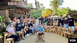 志记鎅木厂负责人王鸿权(蓝衬衫者)与9月3日木工班参加者合照,他们将当日亲手制作的小木凳排成半圆形展示 (美国之音/汤惠芸)