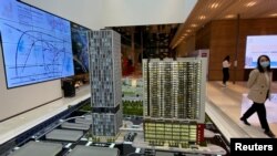 一名女子走过中国深圳凯撒集团开发的一个楼盘销售模型。(2021年11月10日)