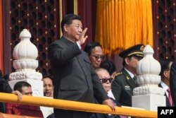 2019年10月1日: 纪念中华人民共和国成立70周年的阅兵式上中国国家主席习近平(左)挥手。