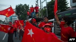 Supporters of the National League for Democracy (NLD) party wave flags in front of the party's headquarters in Yangon on November 9, 2020, as NLD officials said they were confident of a landslide victory in the weekend's election. (Photo by Ye Aung Thu /